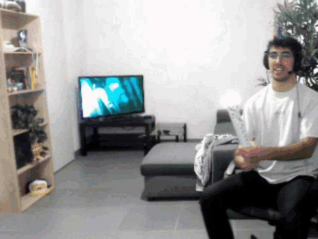 a man wearing headphones is sitting in front of a flat screen tv