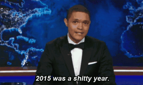 a man in a tuxedo is giving a speech on a stage and says 2015 was a shitty year .