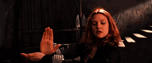 a woman with red hair is holding her hands up in the air .