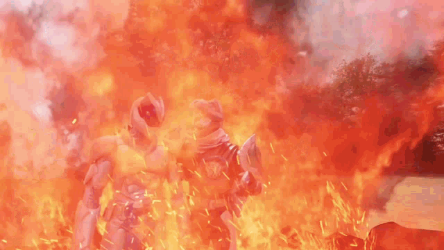 two superheros are standing in front of a fire .