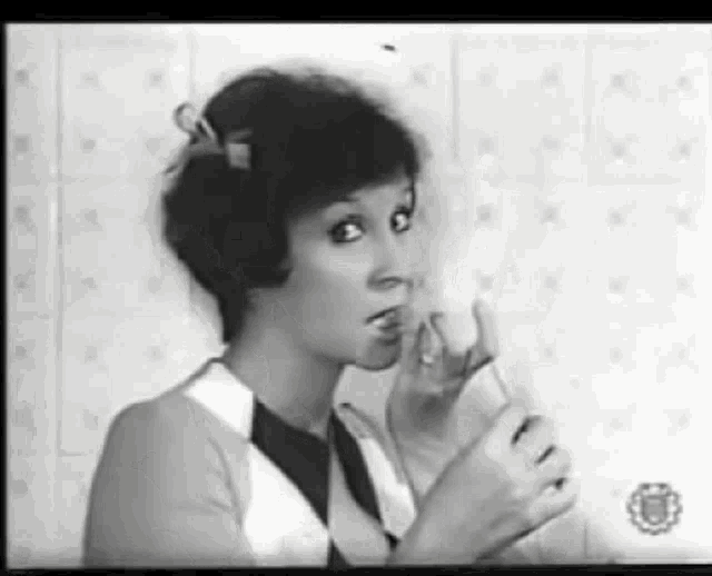 a black and white photo of a woman making a face with her hands .