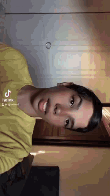 a young man in a yellow shirt is making a funny face with his mouth open