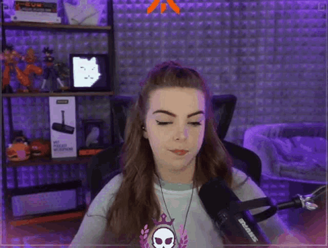 a woman is sitting in front of a microphone with her eyes closed and a skull necklace .