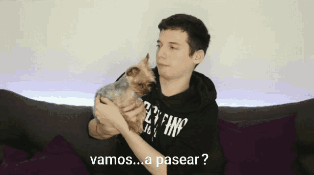 a man holding a small dog with the words vamos a pasear written below him