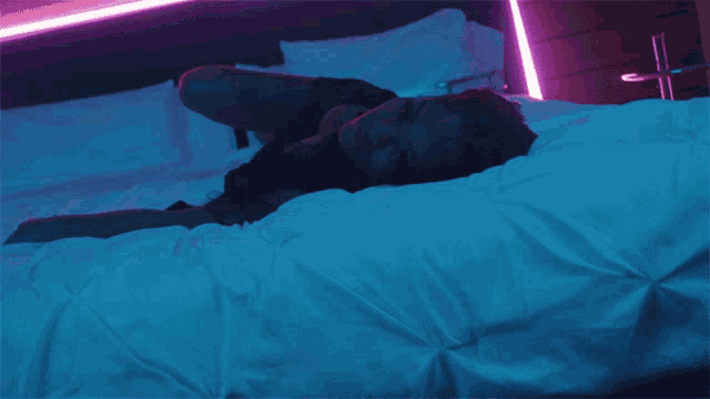a woman is laying on a bed under a blue light