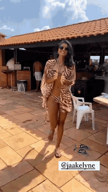 a woman in a bikini is walking in front of a building with the name jaakelyne on the bottom