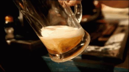 a glass of beer is being poured into a glass on a table