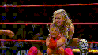 two women are wrestling in a ring and one of them is holding the other on her shoulders .