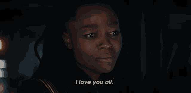 a woman with dreadlocks is saying i love you all in a dark room