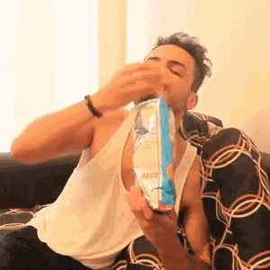 a man is sitting on a couch and eating a bag of chips