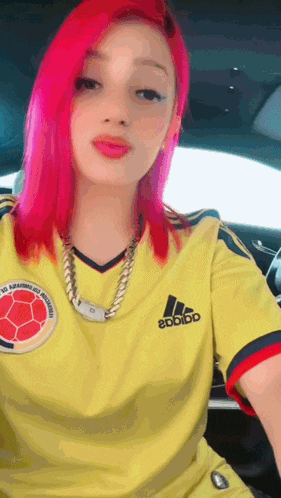 a woman with pink hair is wearing an adidas shirt