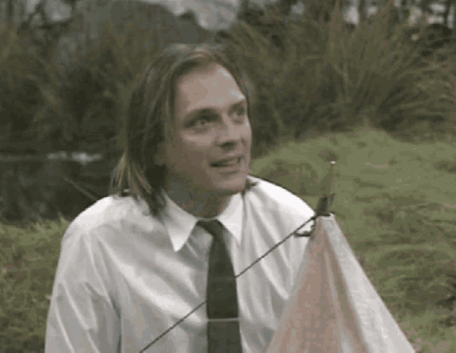a man in a white shirt and tie is holding a sailboat