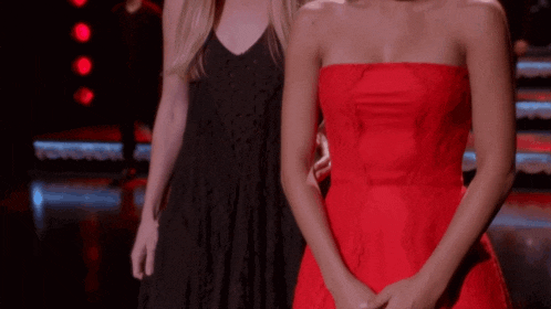 a woman in a black dress and a woman in a red dress stand next to each other
