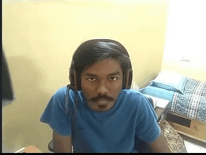 a young man wearing headphones and a blue shirt is sitting in a room .