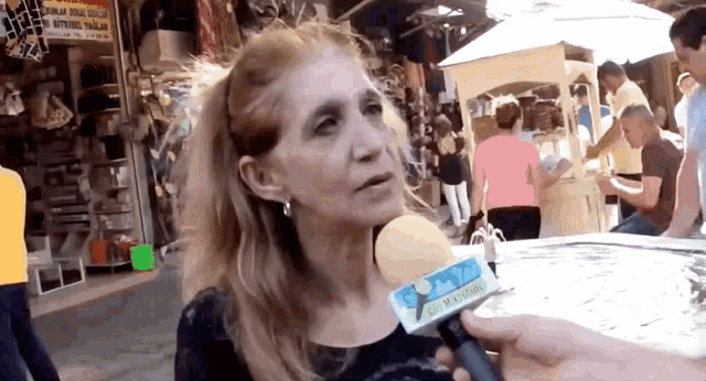a woman is being interviewed with a microphone that says ' izmir ' on the front