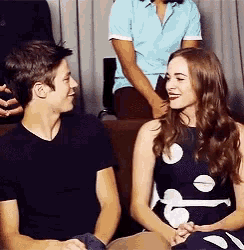 a man and a woman are sitting next to each other on a couch and looking at each other .