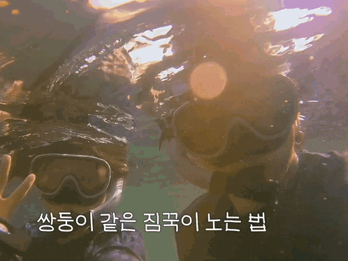 a man and a woman are swimming in the water with korean writing on the bottom