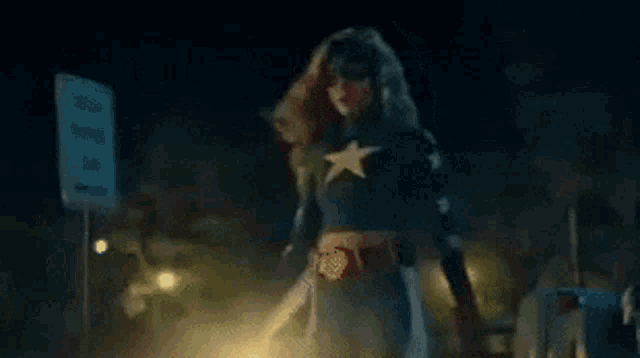 a woman in a superhero costume is holding a light beam in her hand .