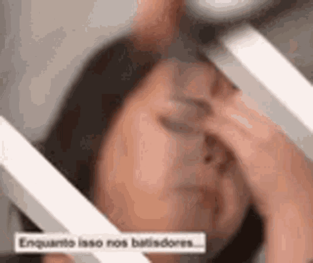 a woman is covering her face with her hand while looking down .