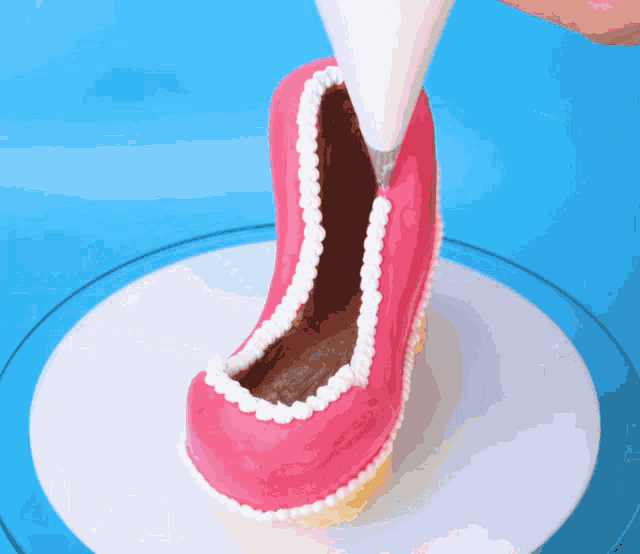a pink shoe shaped cake is being decorated with white icing