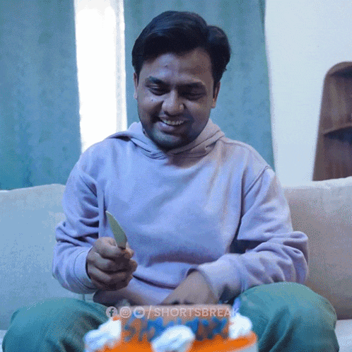 a man is sitting on a couch with a birthday cake in front of him and the words shortsbreak on the bottom