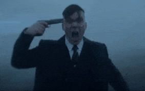 a man in a suit is holding a gun to his head .