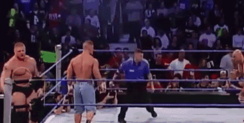 a referee is standing in the middle of a wrestling ring with two men .
