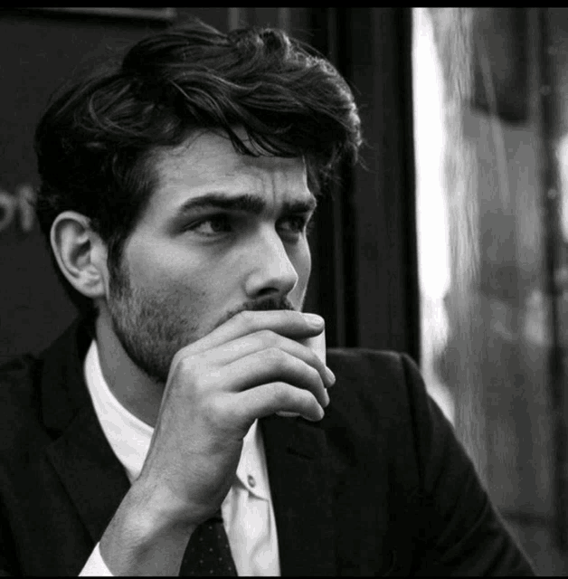 a black and white photo of a man covering his mouth with his hand
