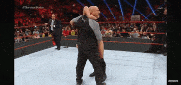 a man is carrying another man in a wrestling ring while a crowd watches .