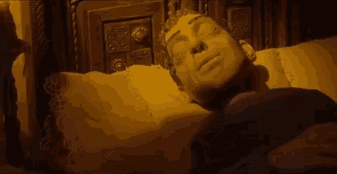 a statue of a man is laying in bed with his eyes closed .