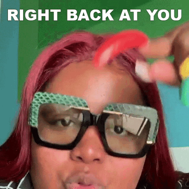 a woman with red hair and glasses is wearing a wig and a wig .