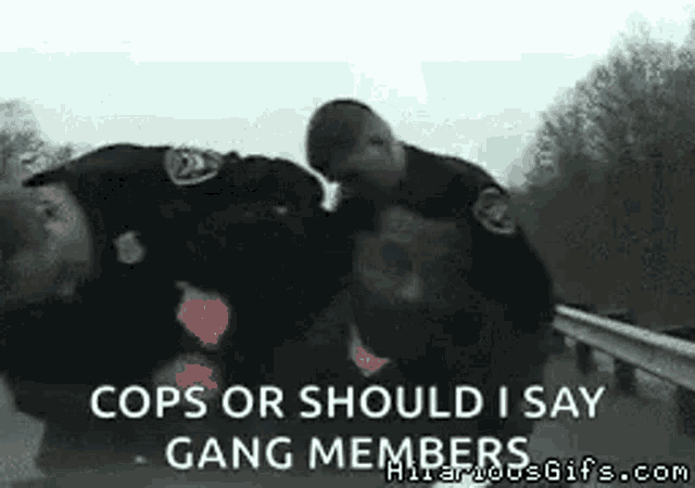 two police officers are fighting a man on the side of a road .