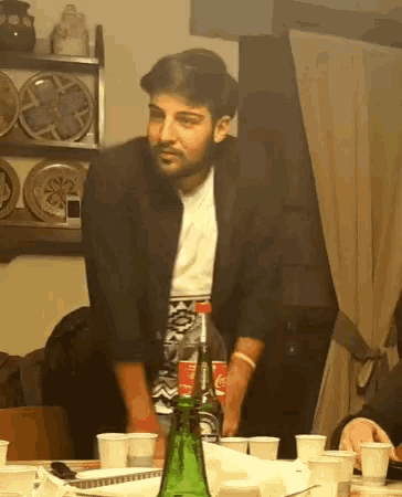 a man stands in front of a table with a bottle of coca cola on it
