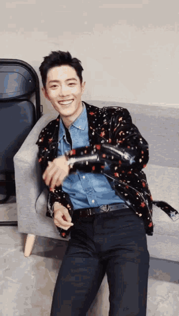 a man is sitting on a couch wearing a jacket and a denim shirt .