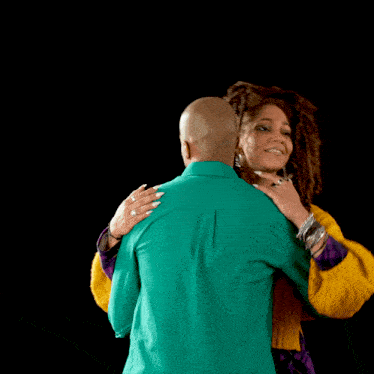 a man in a green shirt and a woman in a yellow sweater are dancing