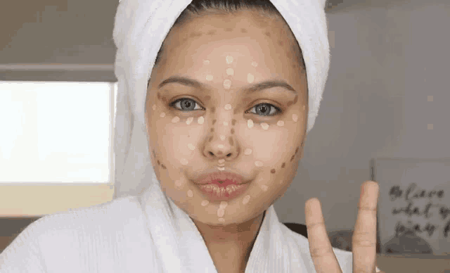 a woman with a towel wrapped around her head has a lot of foundation on her face