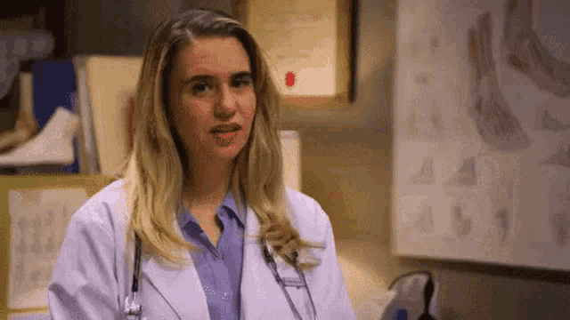 a woman in a white lab coat and stethoscope is standing in a room .