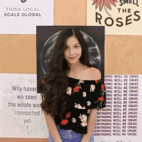 a woman with long hair is standing in front of a wall with posters on it .
