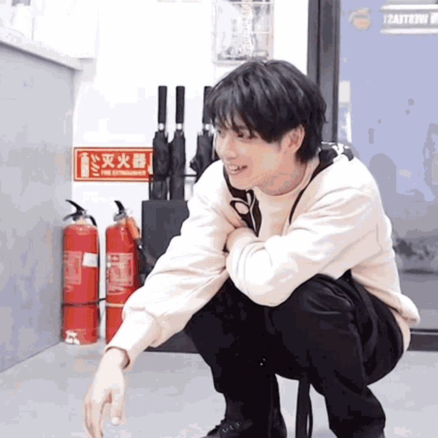 a man is squatting down in front of a fire extinguisher