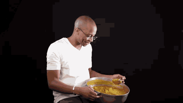 a man in a white shirt is holding a bowl of yellow liquid