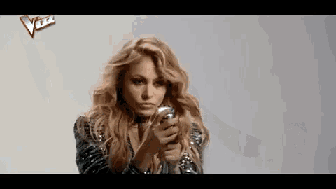 a woman in a sequined jacket is holding a microphone .