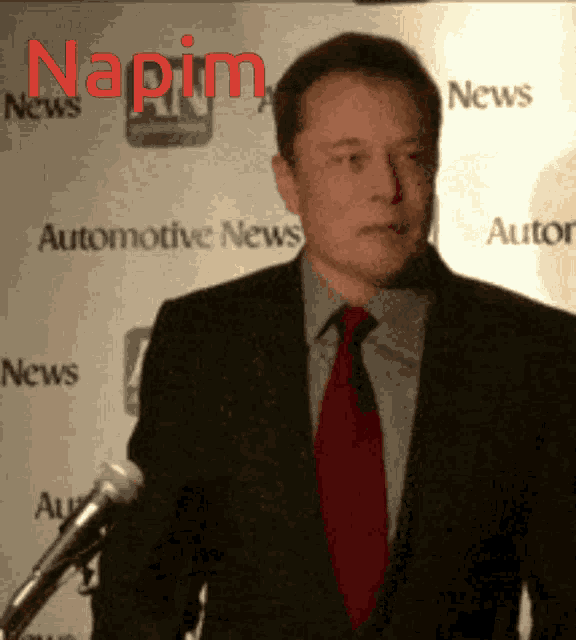 a man in a suit and tie stands in front of a microphone with the word napim in red letters