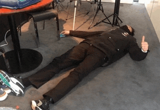 a man laying on the floor giving a thumbs up sign