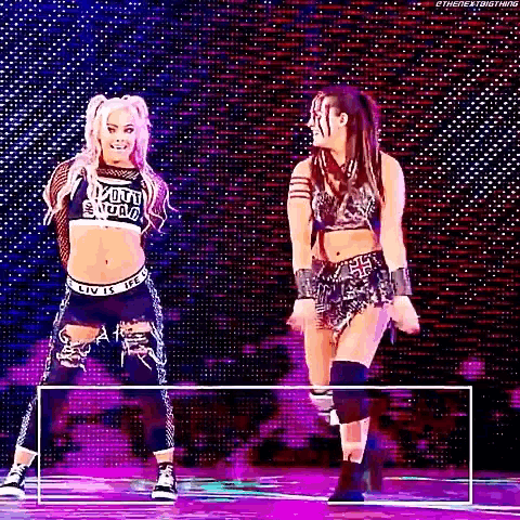 two women are standing next to each other on a stage in front of a crowd .