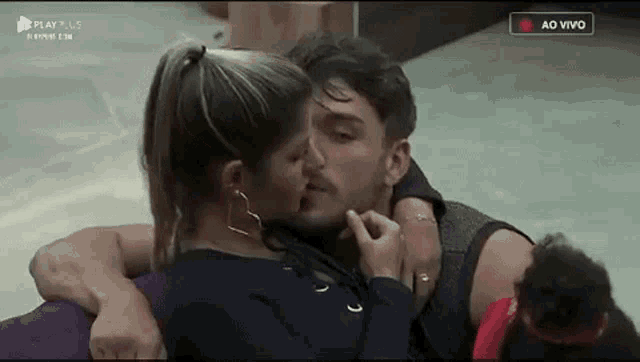 a man and a woman are kissing in a room while sitting on a couch .