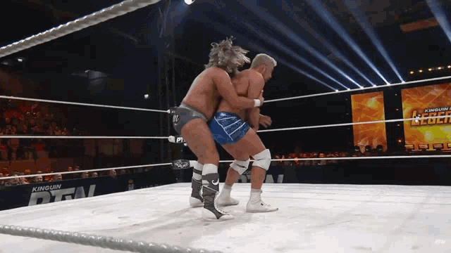 two men are wrestling in a ring with a sign that says kinglum