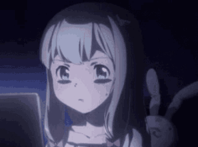 a girl is sitting in front of a laptop computer with a bunny behind her .