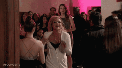 a woman is dancing in a room with a crowd of people .
