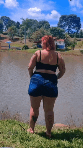 a woman in shorts stands in front of a lake