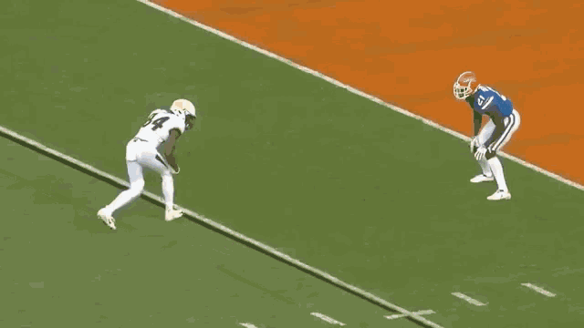 a football player wearing the number 77 is being tackled by a player wearing the number 92